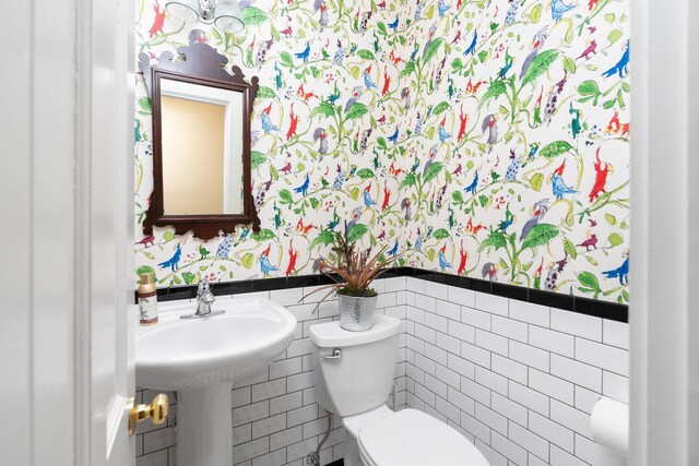 bathroom featuring toilet and tile walls