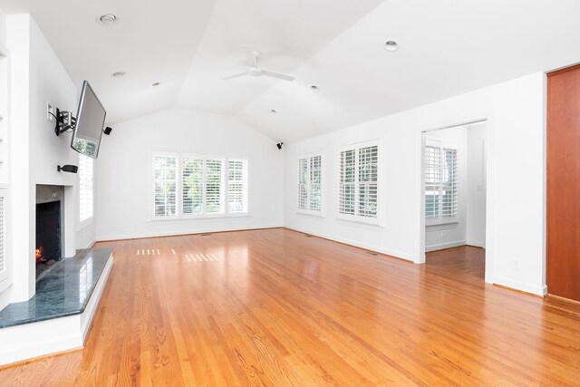 unfurnished living room with plenty of natural light, lofted ceiling, ceiling fan, and light hardwood / wood-style flooring