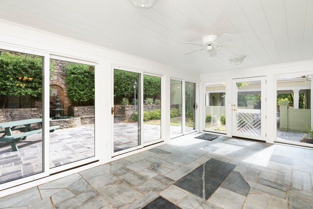 unfurnished sunroom featuring wood ceiling, plenty of natural light, and ceiling fan