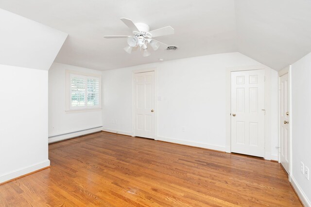 additional living space featuring baseboard heating, ceiling fan, vaulted ceiling, and light hardwood / wood-style floors