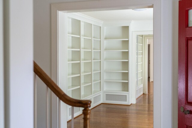 corridor featuring crown molding, dark wood-type flooring, and built in features