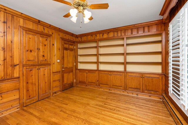 interior space with wooden walls, light hardwood / wood-style floors, and ceiling fan