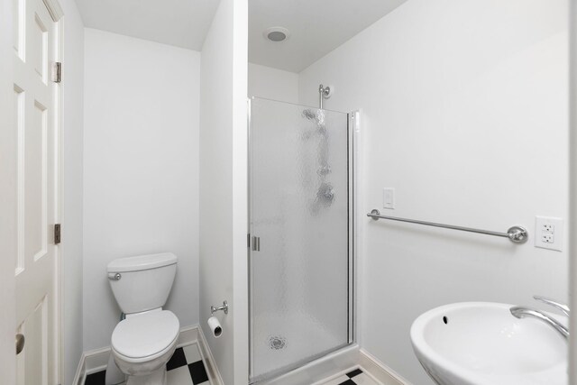 bathroom with sink, an enclosed shower, and toilet