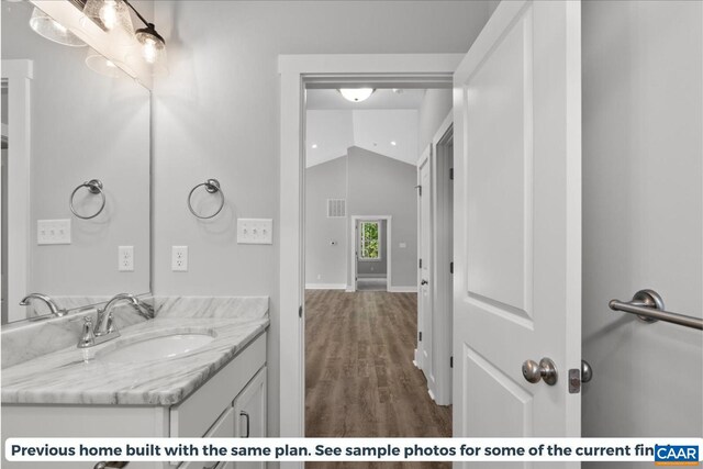 bathroom featuring lofted ceiling, vanity, and hardwood / wood-style floors