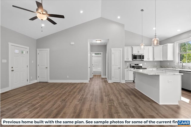 kitchen with dark wood-type flooring, a center island, pendant lighting, stainless steel appliances, and white cabinets