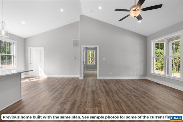 unfurnished living room with dark wood-type flooring, a healthy amount of sunlight, and high vaulted ceiling