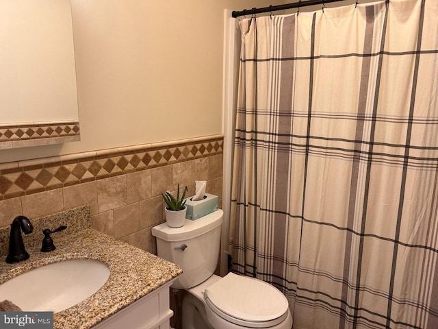 bathroom featuring vanity, tile walls, and toilet