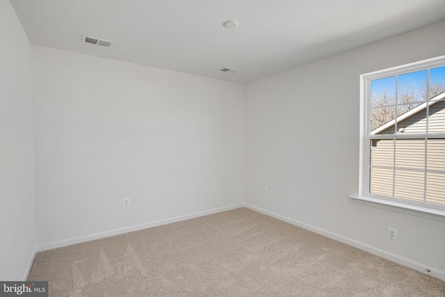 unfurnished room with baseboards, visible vents, and light colored carpet