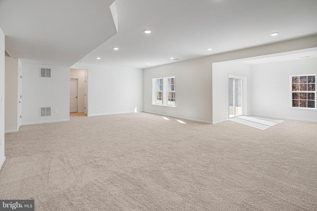 empty room with recessed lighting, light carpet, visible vents, and baseboards