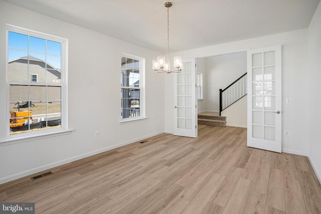 unfurnished dining area featuring light wood-style floors, stairway, a wealth of natural light, and french doors