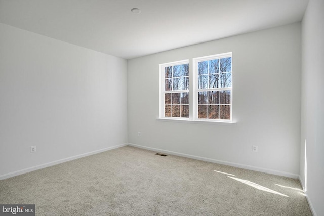 spare room with light carpet, visible vents, and baseboards