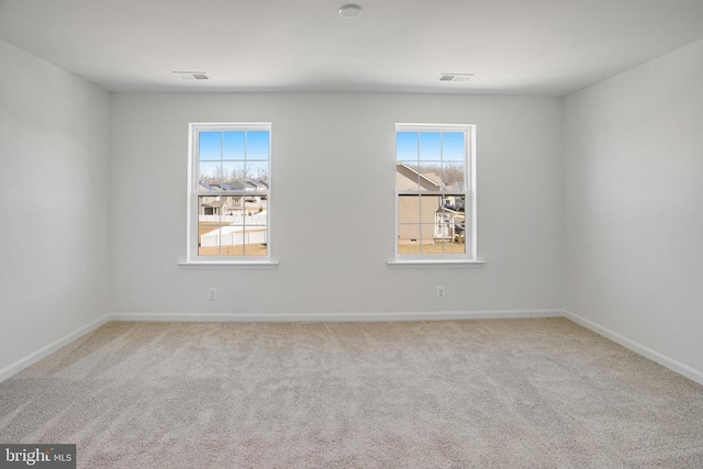 spare room featuring light colored carpet, visible vents, and baseboards