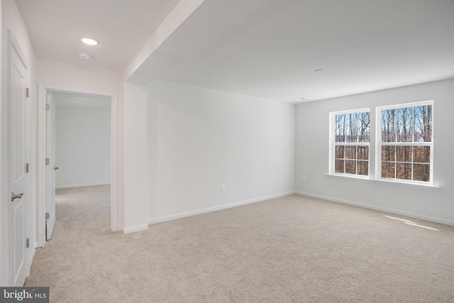 spare room with baseboards and light colored carpet