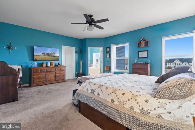 bedroom with ceiling fan, light colored carpet, and ensuite bathroom