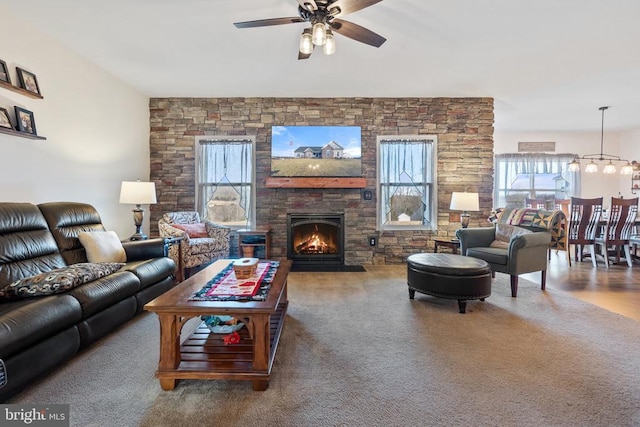 living room with a fireplace and ceiling fan with notable chandelier