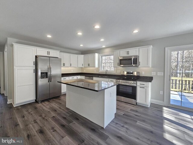 kitchen featuring stainless steel appliances, dark countertops, white cabinets, and a sink