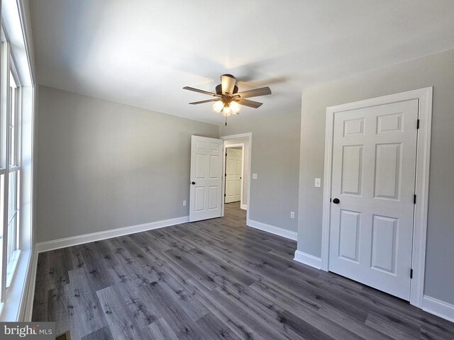 unfurnished bedroom featuring a ceiling fan, dark wood-style flooring, and baseboards