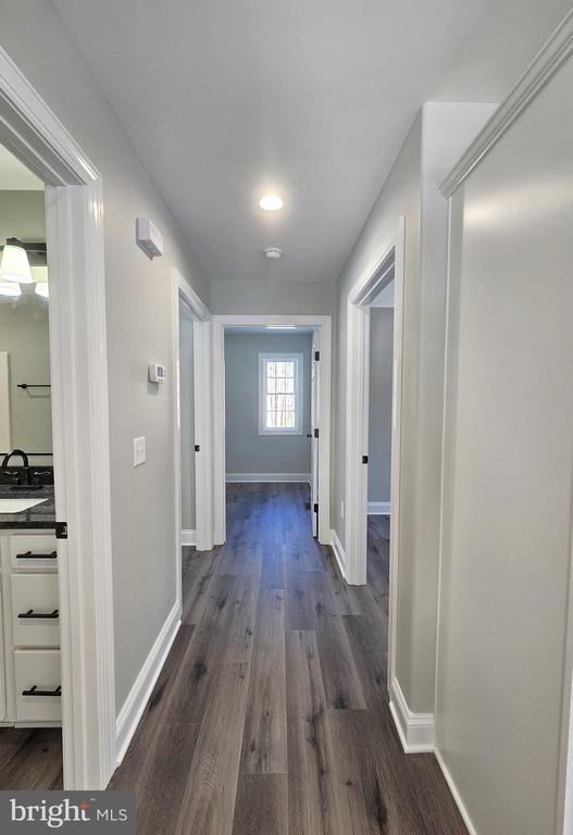 hall featuring dark wood-type flooring, a sink, and baseboards