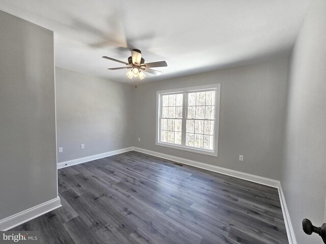 empty room with a ceiling fan, dark wood-style flooring, visible vents, and baseboards