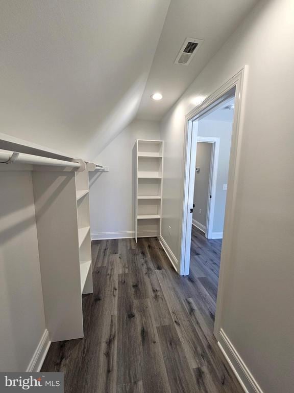 spacious closet featuring lofted ceiling, dark wood-style flooring, and visible vents