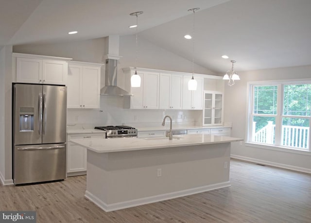 kitchen with wall chimney exhaust hood, appliances with stainless steel finishes, a sink, and white cabinetry