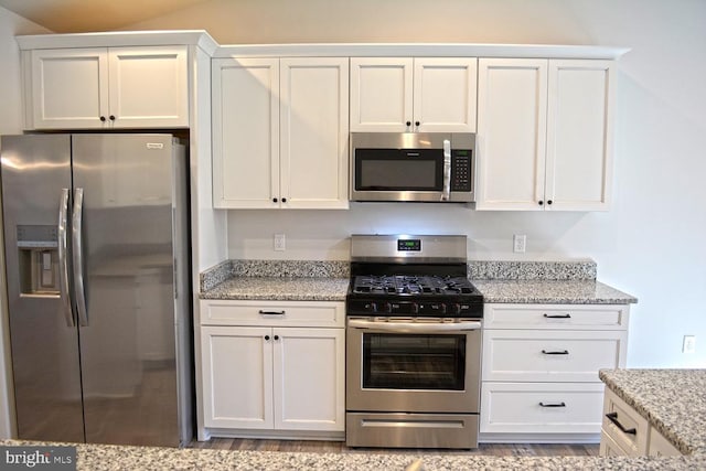 kitchen featuring appliances with stainless steel finishes, light wood-type flooring, white cabinetry, and light stone counters