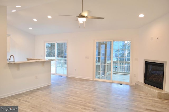 unfurnished living room with baseboards, light wood-type flooring, a fireplace, and recessed lighting