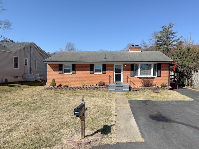 single story home featuring brick siding, a chimney, a front lawn, and a shingled roof