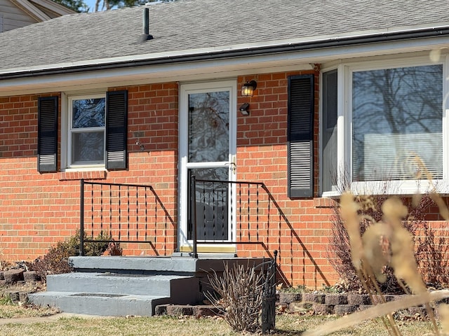 property entrance with brick siding and a shingled roof