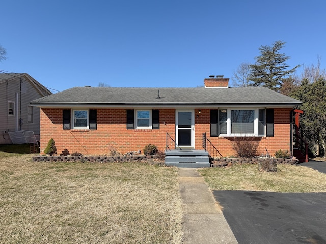 single story home featuring a front lawn, brick siding, roof with shingles, and a chimney