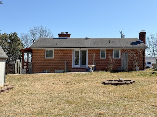 rear view of property with a lawn, french doors, brick siding, and a chimney