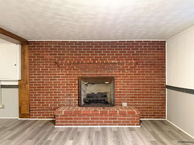 unfurnished living room with a textured ceiling, wood finished floors, and a fireplace