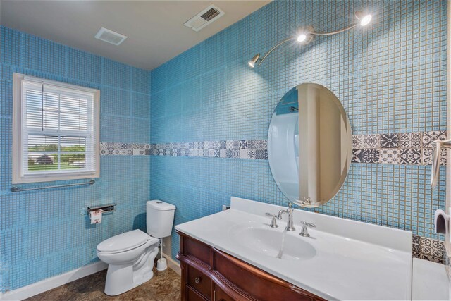 bathroom featuring vanity, toilet, tile patterned flooring, and tile walls