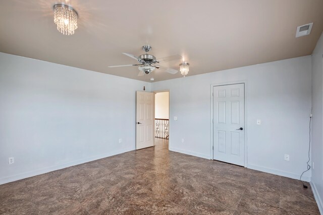 spare room with ceiling fan with notable chandelier