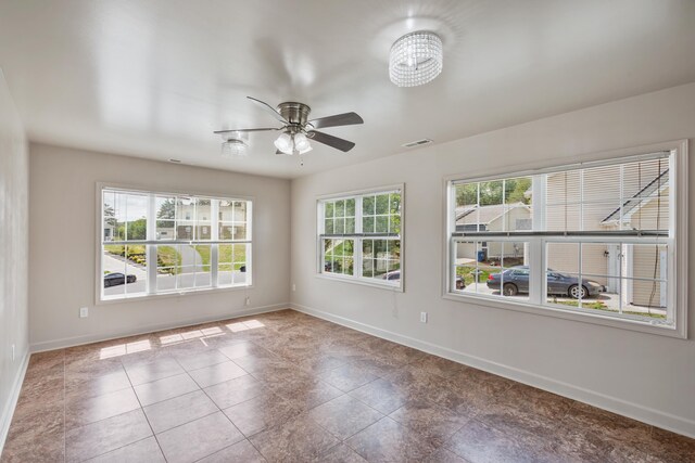 tiled empty room featuring a wealth of natural light and ceiling fan