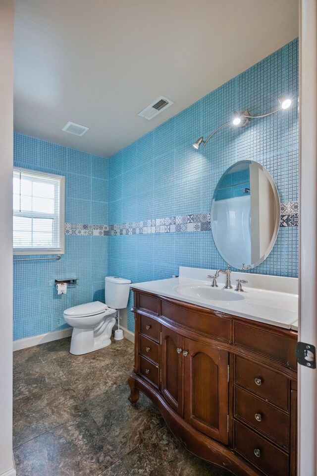 bathroom with vanity, tile walls, and toilet