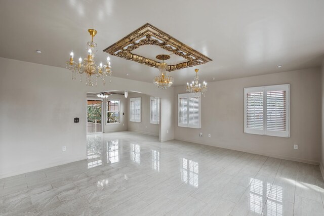 interior space with a tray ceiling and ceiling fan with notable chandelier