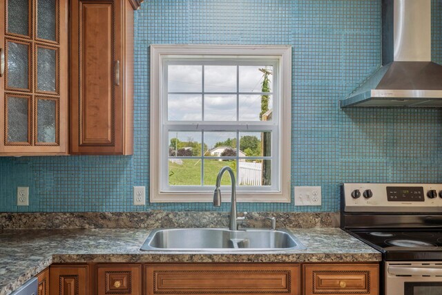 kitchen with appliances with stainless steel finishes, wall chimney exhaust hood, sink, and decorative backsplash