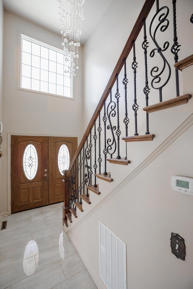 entryway with a towering ceiling and a chandelier