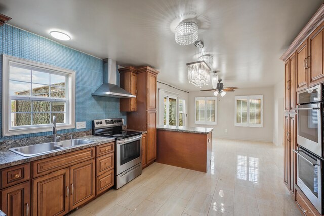 kitchen with wall chimney exhaust hood, sink, ceiling fan, stainless steel appliances, and backsplash