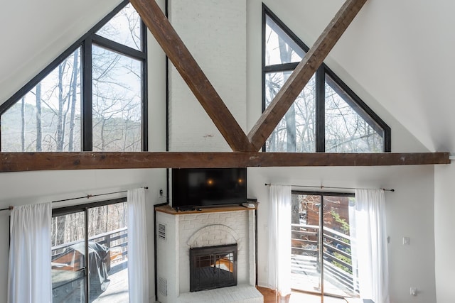 unfurnished living room featuring a towering ceiling and a brick fireplace