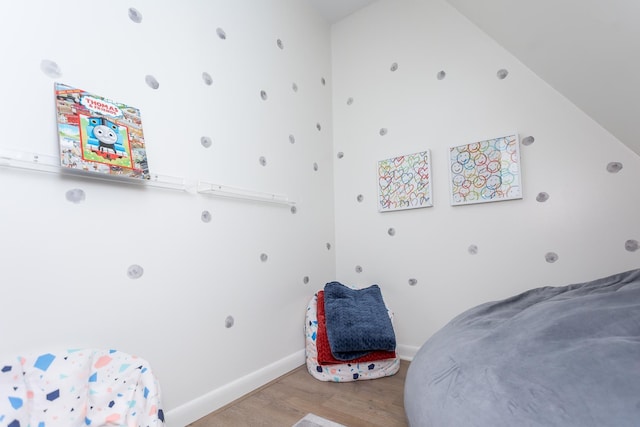 bedroom with lofted ceiling, baseboards, and wood finished floors