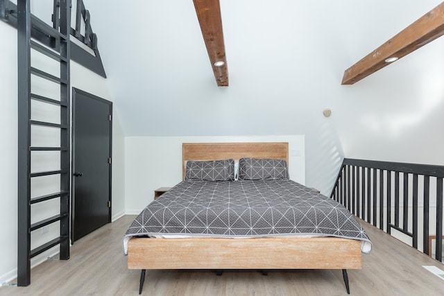 bedroom with beamed ceiling, wood finished floors, and baseboards