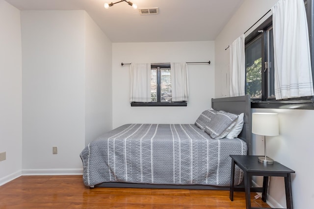 bedroom featuring visible vents, baseboards, and wood finished floors