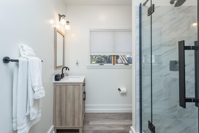 bathroom featuring wood finished floors, a shower stall, vanity, and baseboards