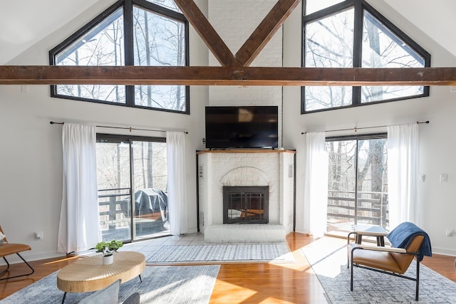 living area with a brick fireplace, baseboards, a wealth of natural light, and wood finished floors