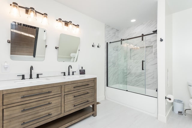 bathroom with double vanity, combined bath / shower with glass door, a sink, and toilet