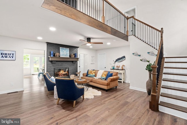living area featuring a fireplace, wood finished floors, stairway, baseboards, and recessed lighting