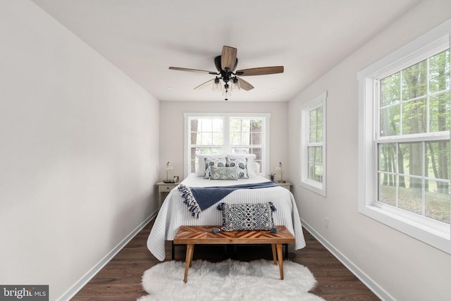 bedroom with ceiling fan, baseboards, multiple windows, and wood finished floors