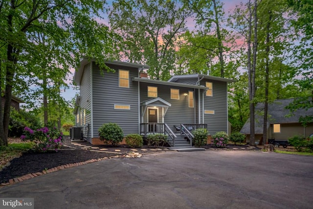 view of front of house with central AC unit and aphalt driveway